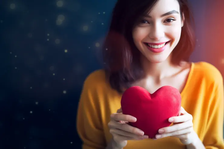 Smiling young woman holding a red heart-like object in her hands