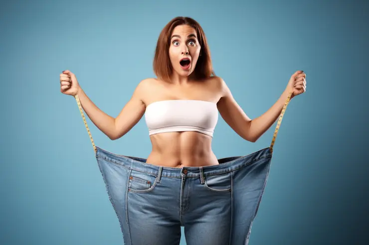 Woman showing off old jeans and the level of weight loss