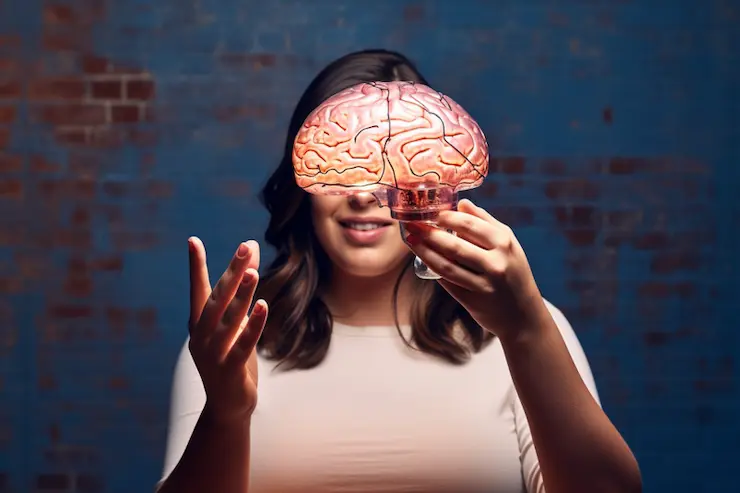 Woman watching and holding a plastic human brain moulage with electric-like charges