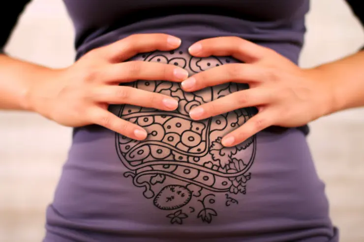Woman holding her belly that has a drawing of a digestive system