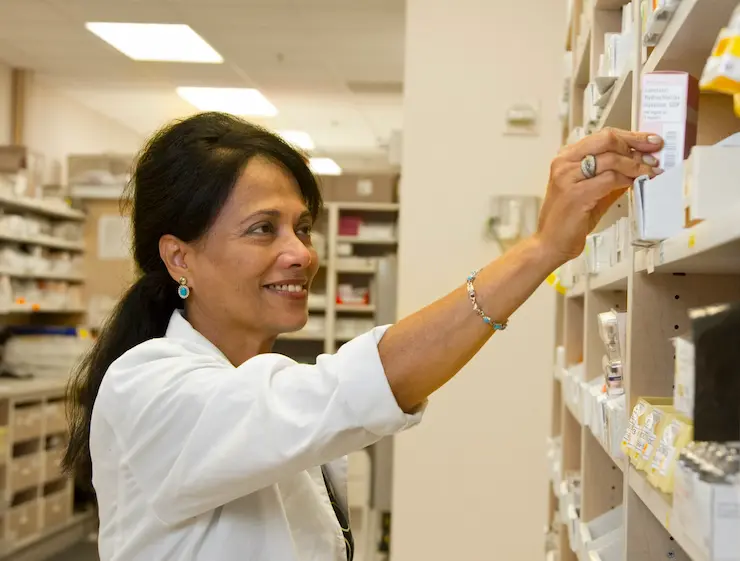 A female pharmacologist checking medicine on the shelves